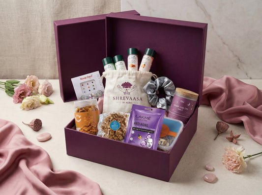 Purple gift box with various items including a bag labeled 'Shreevaasa' on a light background.